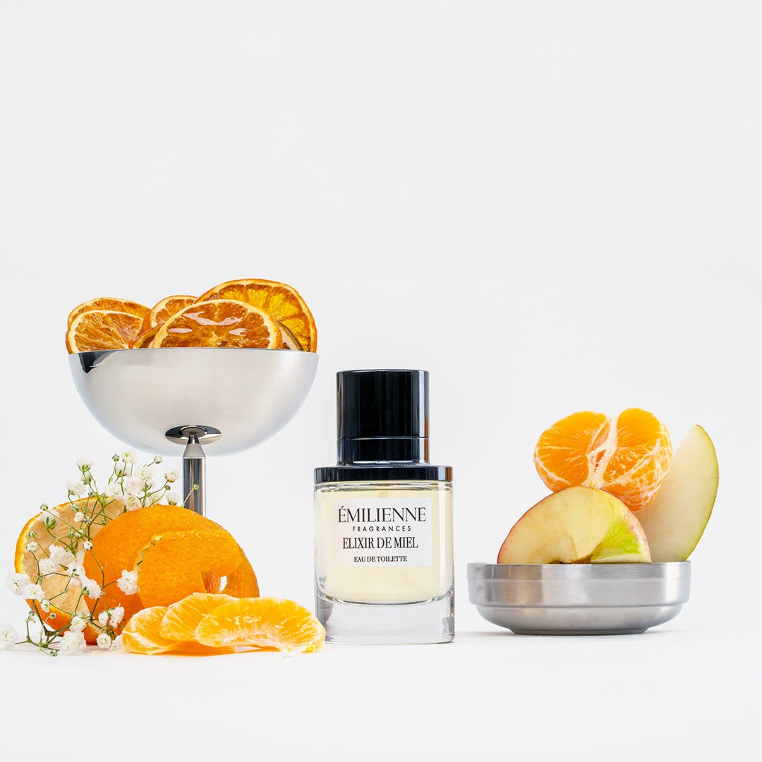 Emile Benne perfume bottle with oranges and flowers on a white background